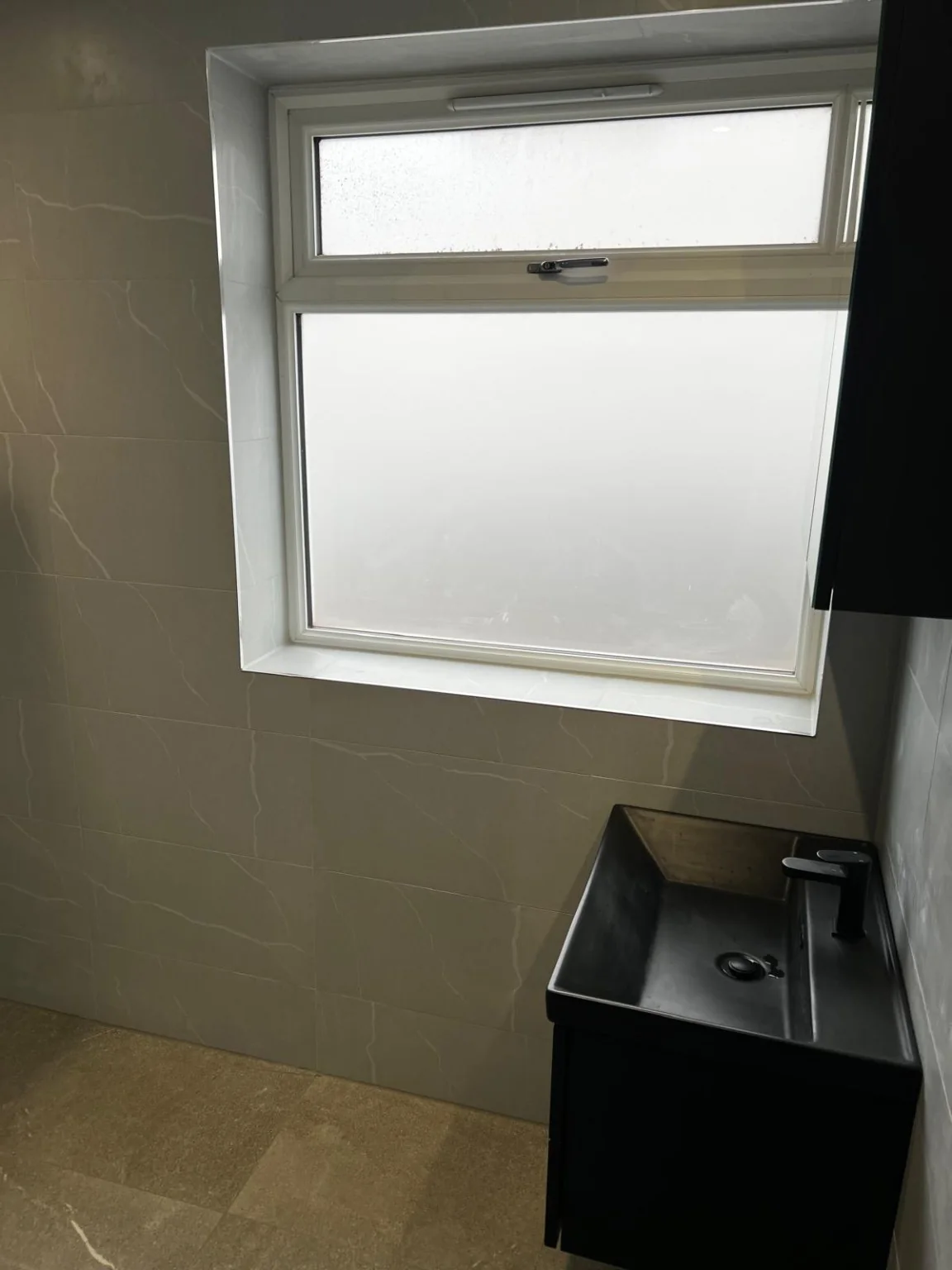 Bathroom renovation with black basin by window