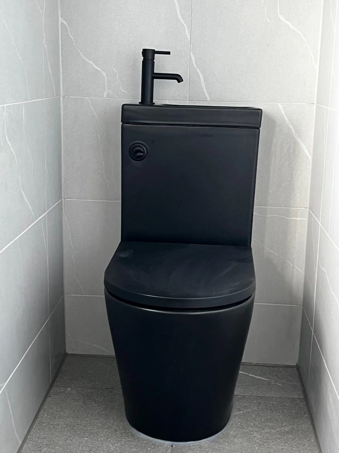Black toilet with integrated handwashing basin close-up
