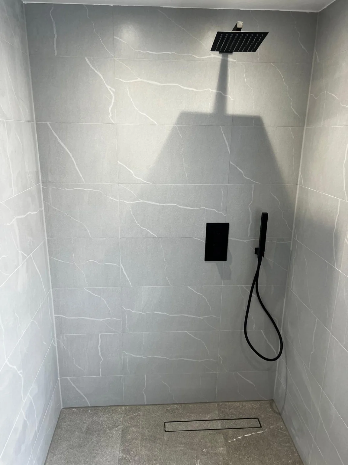 Completed walk-in shower with grey wall tiles