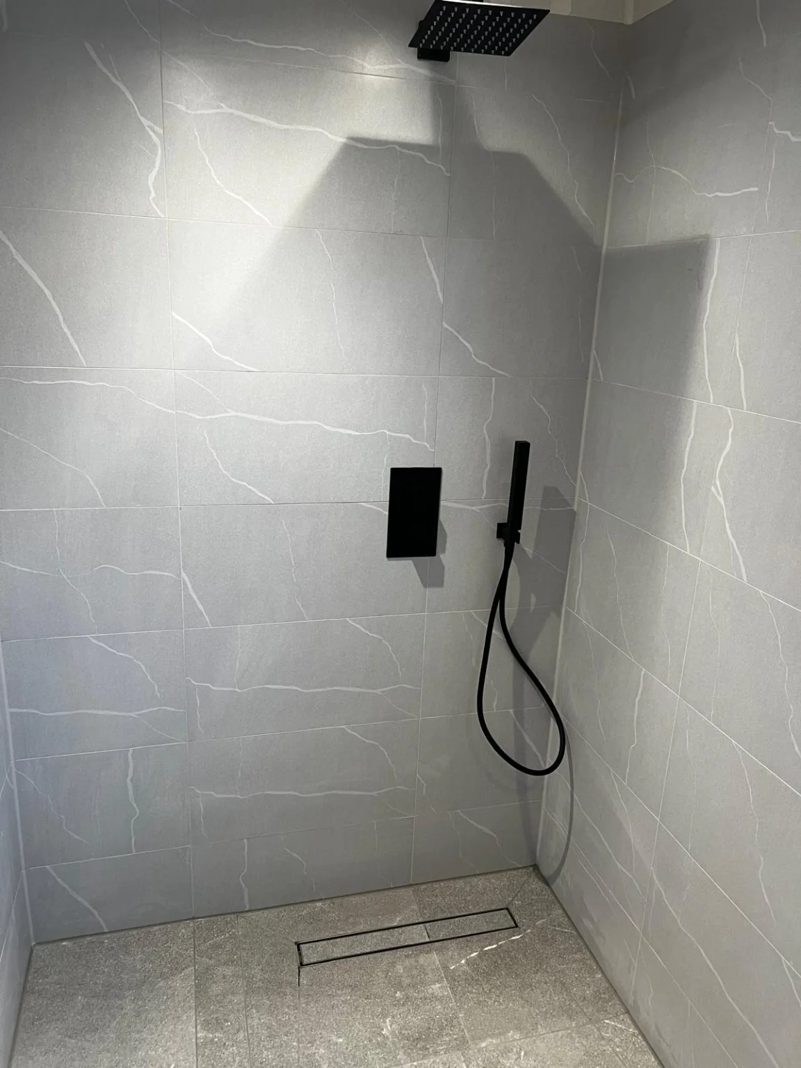 Grey tiled walk-in shower with black fixtures